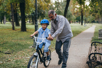 boy with his grandfather riding bike public park