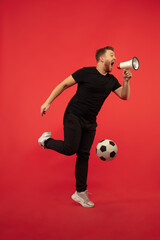 Fototapeta na wymiar Shouting football fan with ball, goal. Full length portrait of young man isolated on red studio background. Attractive male caucasian model. Copyspace. Human emotions, sport, facial expression concept