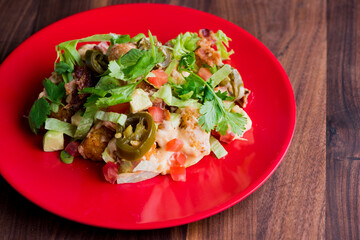 Nachos. Crispy tortilla chips topped with melted cheddar cheese, salsa, black beans, jalapenos, guacamole, sour cream and lettuce. Tex-Mex or Mexican restaurant classic traditional menu item. 