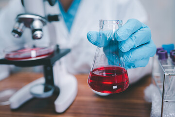 Asian scientist biochemist or microbiologist working research with a microscope in laboratory. For protect outbreak Coronavirus Covid19, bacteria and germs.