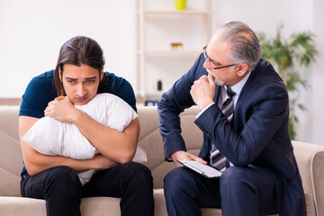 Young man visiting old male psychologist