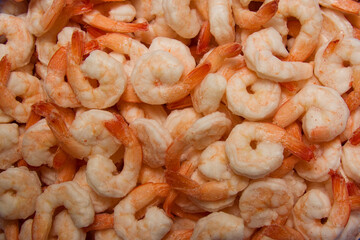 Close-up of a heap of frozen peeled orange shrimp. Natural seafood background. Top view, vertical format.