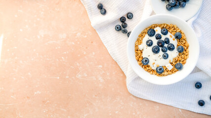 Delicious homemade muesli and blueberries served on a beige table with a white napkin, top view with space for text. Healthy breakfast