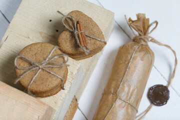 Gingerbread cookies tied with twine. Nearby are wooden blocks. On boards painted white.