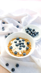 Delicious homemade muesli and blueberries served on a beige table with a white napkin, top view with space for text. Healthy breakfast