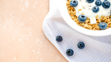 Delicious homemade muesli and blueberries served on a beige table with a white napkin, top view with space for text. Healthy breakfast