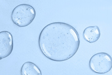 Drops of liquid transparent gel with bubbles on a blue background.