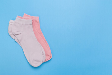 two pairs of multicolored new socks stacked on a blue background. top view.