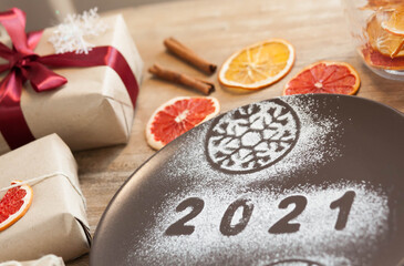 Obraz na płótnie Canvas Christmas and New Year 2021 background with a festive plate with the inscription 2021 and boxes of gifts
