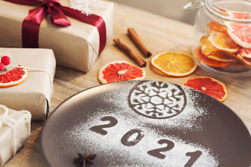 Obraz na płótnie Canvas Christmas and New Year 2021 background with a festive plate with the inscription 2021 and boxes of gifts