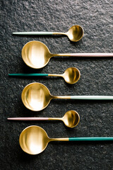 elegant large and small spoons arranged strategically. Flat View.black background
