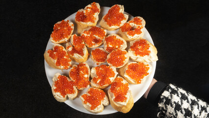 Sandwiches with red caviar and butter on baguette on the dark background. Cuisine concept.