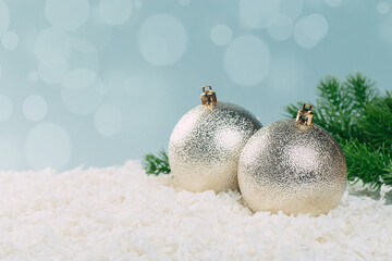 branch of a Christmas tree with Christmas balls in the snow on a blue background with bokeh lights....