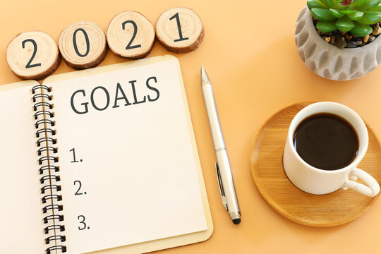 Business concept of top view 2021 goals list with notebook, cup of coffee over pastel yellow background