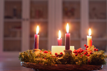 Advent wreath with candles burning in light room