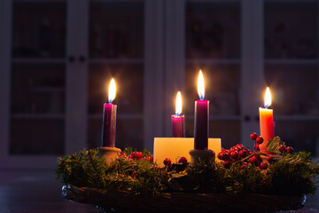 Advent wreath with candles burning in dark room