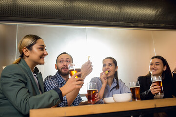 Laughting. Happy co-workers celebrating corporate event after tensioned work day. Look delighted, friendly, cheerful. Drinking beer. Concept of office culture, teamwork, friendship, holidays, weekend.