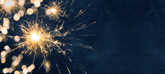 Silvester party New year background banner panorama long- sparklers and bokeh lights on dark blue night sky texture, with space for text	