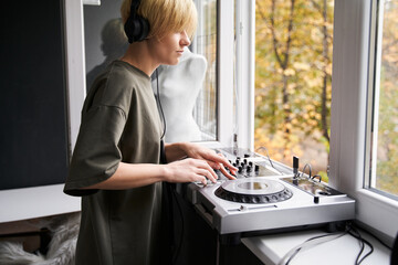 Musician wearing headphones using dj console