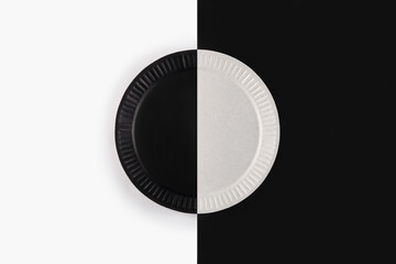 Minimal composition with black and white paper dish on black and white background, top view. Eco-friendly disposable tableware from natural material. Ecological concept.