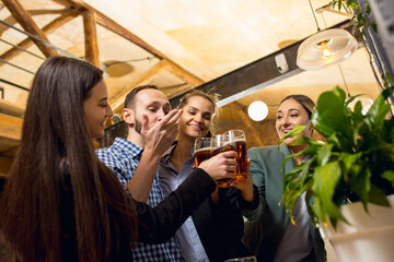 Clinking. Happy co-workers celebrating corporate event after tensioned work day. Look delighted, friendly, cheerful. Drinking beer. Concept of office culture, teamwork, friendship, holidays, weekend.