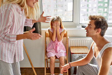 little daughter girl is closing her eyes, she is scared of parents quarrel at home, broken family, divorce concept