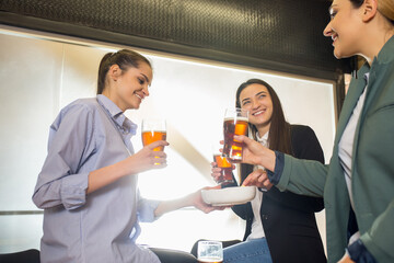 Talks. Happy co-workers celebrating corporate event after tensioned work day. Look delighted, friendly, cheerful. Drinking beer. Concept of office culture, teamwork, friendship, holidays, weekend.