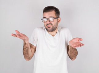 Portrait of attractive beard man wearing white casual shirt showing I don't know gesture isolated over white background
