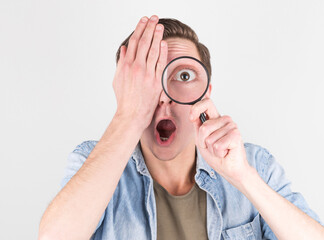 Shocked man looking through a magnifying glass