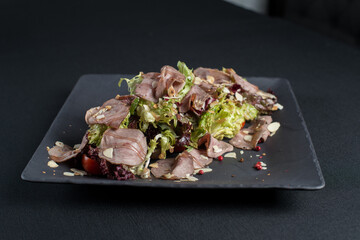 Salad with smoked duck meat, sweet and sour sauce with almonds flakes
