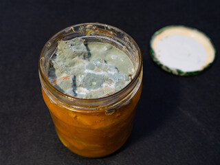 A jar with spoiled expired jam, covered with mold. Storage of jam and spoilage. 