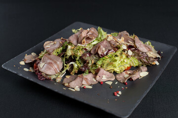 Salad with smoked duck meat, sweet and sour sauce with almonds flakes