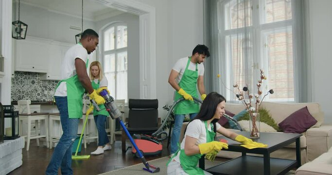 Good-looking professional hardworking smiling mixed race cleaners from cleaning service working together in customer house,service industries concept
