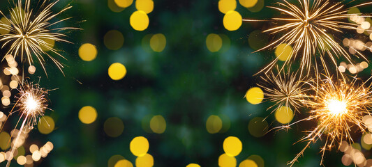 Silvester background banner panorama - Golden yellow firework, sparklers and bokeh lights on dark green texture, with space for text