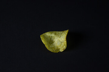 Chips on a black background. Unhealthy food. One chip in the middle of the frame