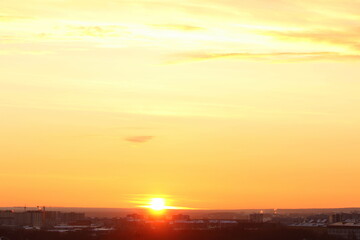 Sun below the horizon and clouds in the fiery dramatic orange sky at sunset or dawn backlit by the sun. Place for text and design