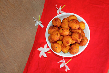 Sugar palm fritters or taler bora in a white bowl on red cloth with white crepe jasmine flower.
