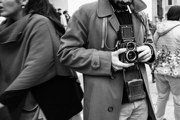 Hipster guy with the vintage camera photographing people in the city - Photojournalist with a...