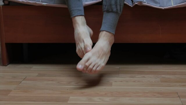 Mans feet on cold floor gets out of bed in the morning