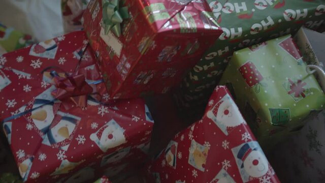 Pan over colorful Christmas presents under tree interior