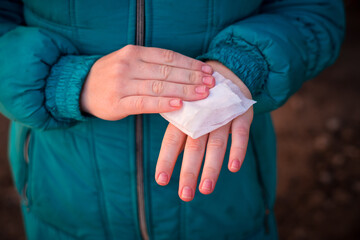 Girl wipes her hands with a napkin outside in frost