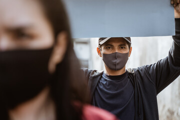 Portrait students holding blank paper conducting demonstrations by following health protocols