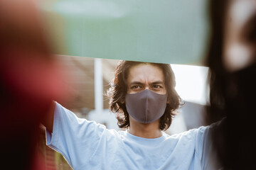 Portrait students holding blank paper conducting demonstrations by following health protocols