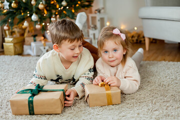 Christmas. Happy kids open gifts near the Christmas tree. Holidays.