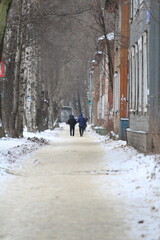 Snowy street with twi departing silhouettes of people, back view