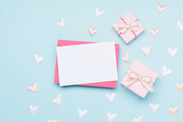 Pink white textile hearts and empty envelope on pastel blue background. Valentines day concept. Flat lay, top view, copy space.