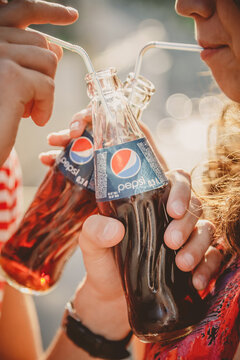 ODESSA, UKRAINE - OCTOBER 15, 2014: Close up of happy young couple outdoors drinking cold Pepsi from glass bottles with straw
