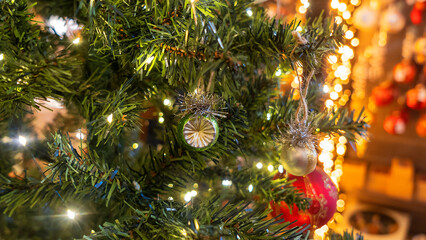 Green ball is on fir Christmas tree. Close-up image of green New Year toy decoration on yellow background. Happy New Year concept.
