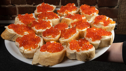 Sandwiches with red caviar and butter on baguette on the dark background. Cuisine concept.