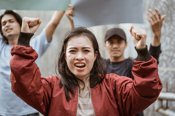 Portrait female students demonstrating with their friends holding blank paper in the background